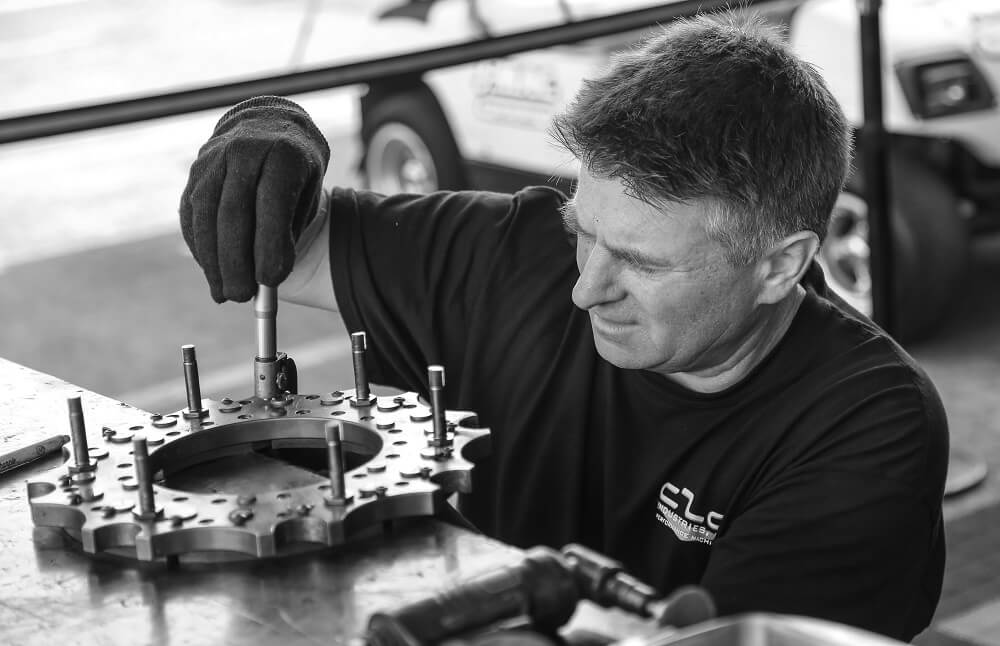 homme avec des gants qui répare un moteur de voiture